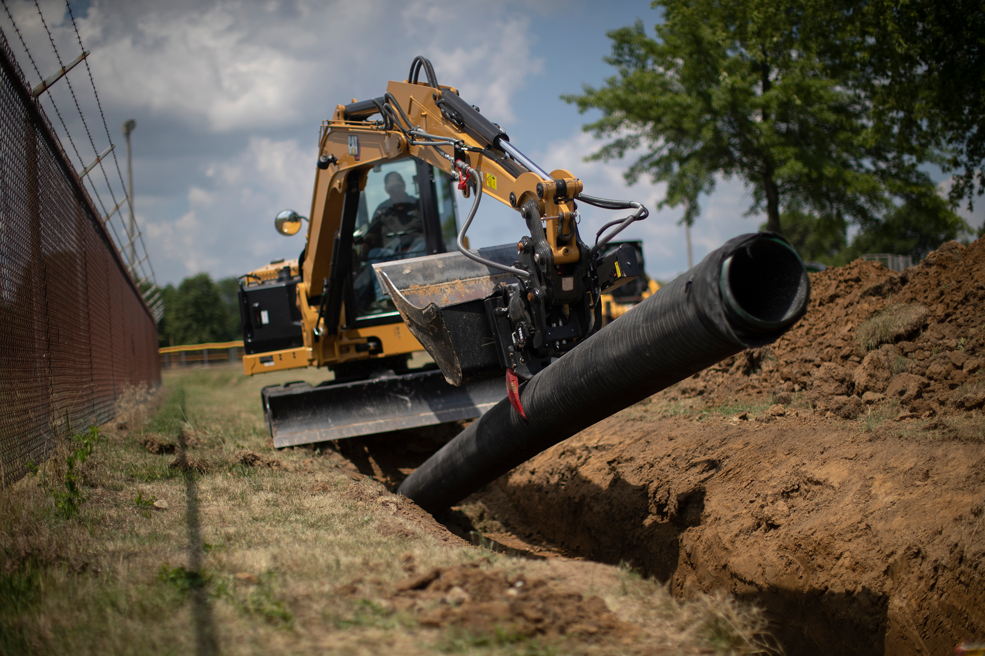 Cat 306CR compact excavator laying pipe
