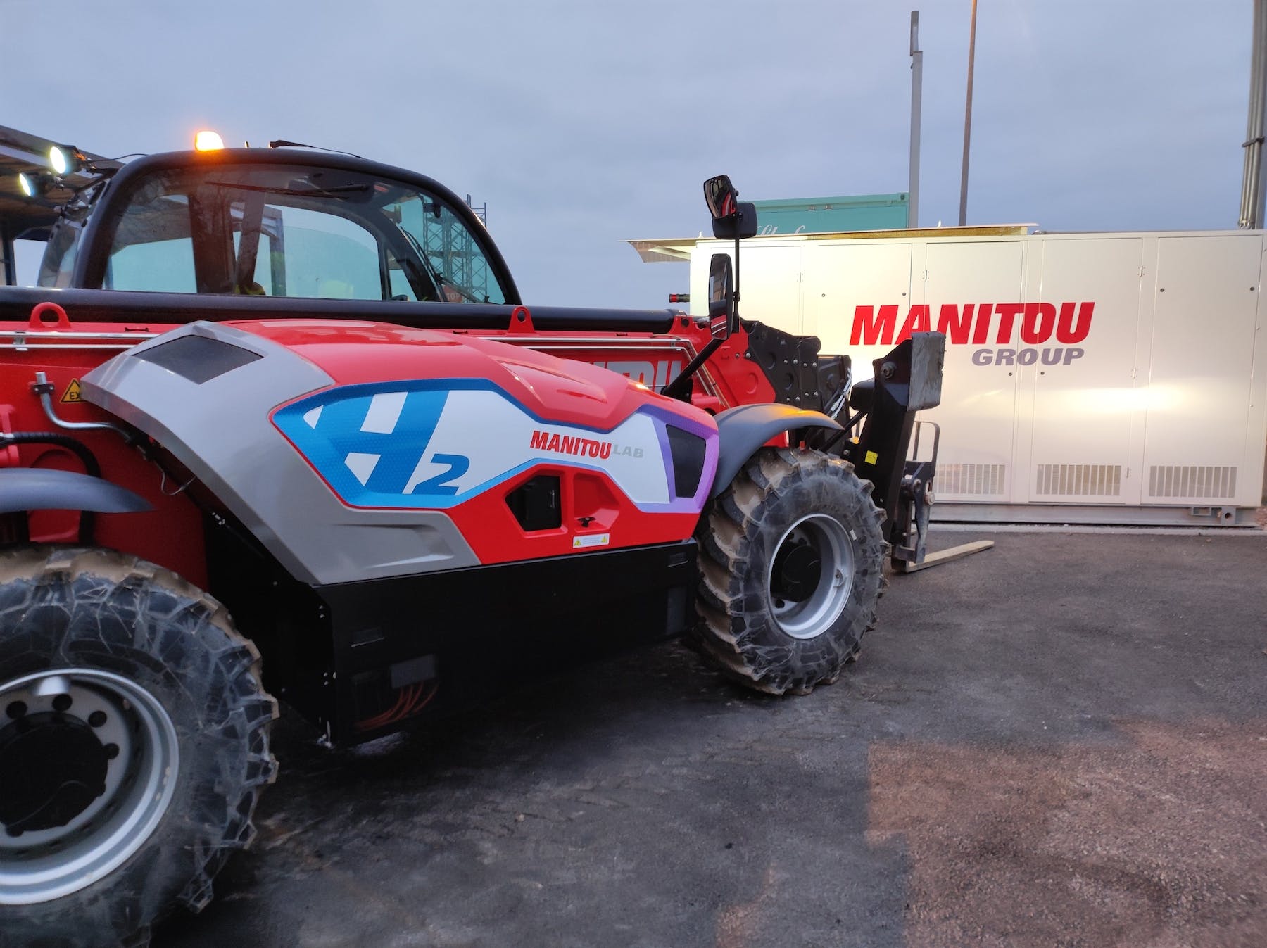 side view Manitou hydrogen telehandler prototype with headlights shining on Manitou Group trailer