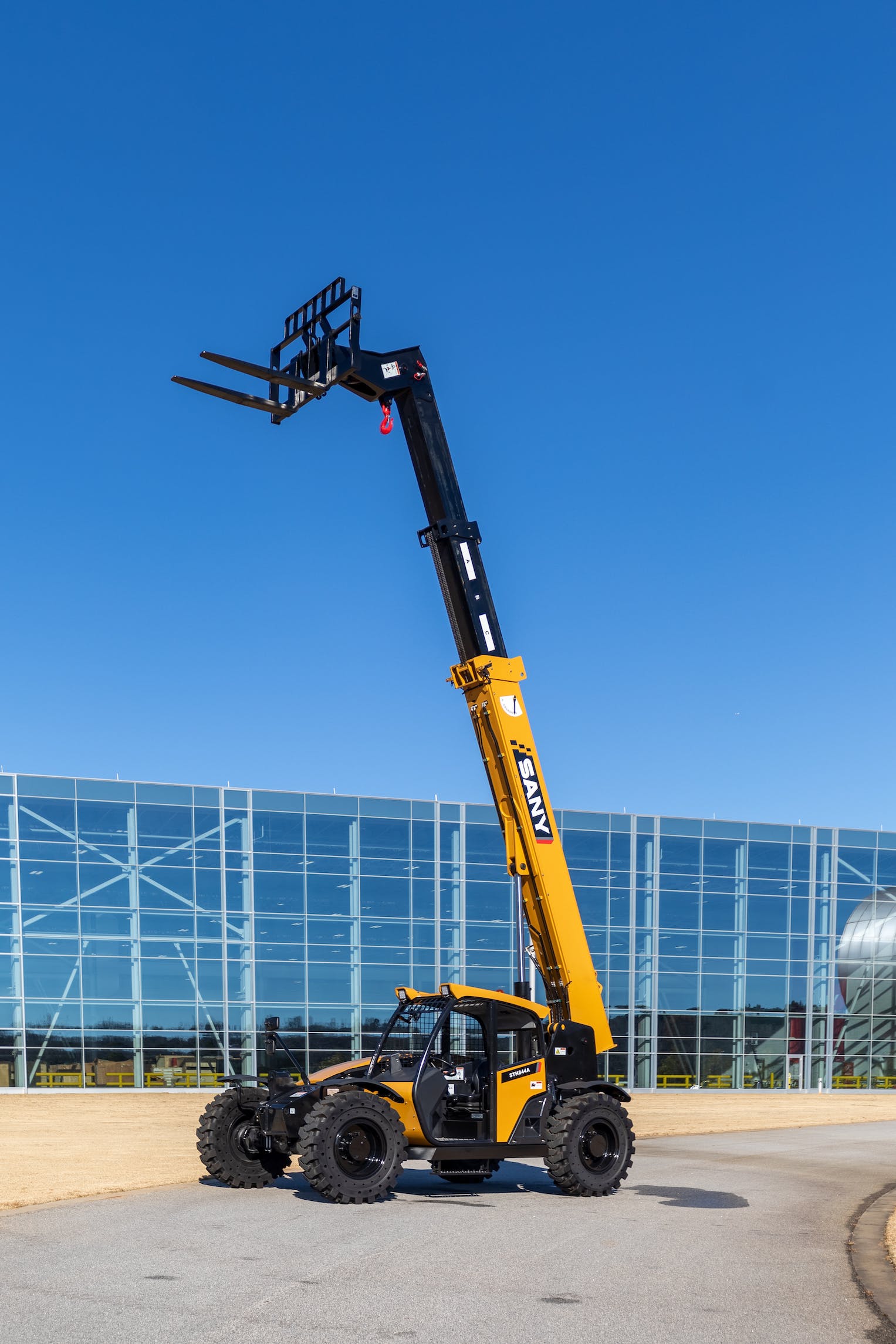 SANY STH844A Telehandler fully extended boom in front of glass building